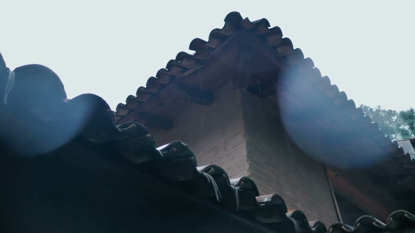 A drone hovering over a shingled roof with a brick chimney during a roof inspection